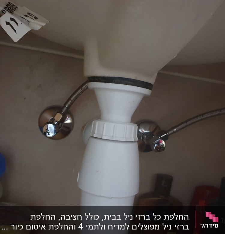 צינור פלסטיק לבן עם חיבורים מתכתיים מתחת לכיור
